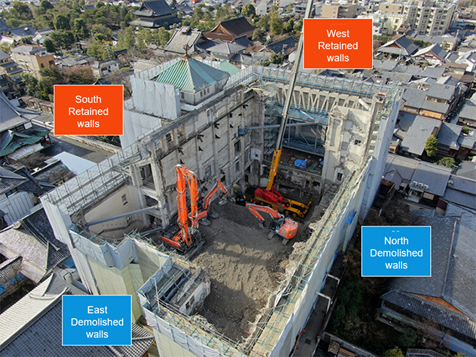Aerial view of a building undergoing demolition, showing retained south and west exterior walls and demolished north and east walls.