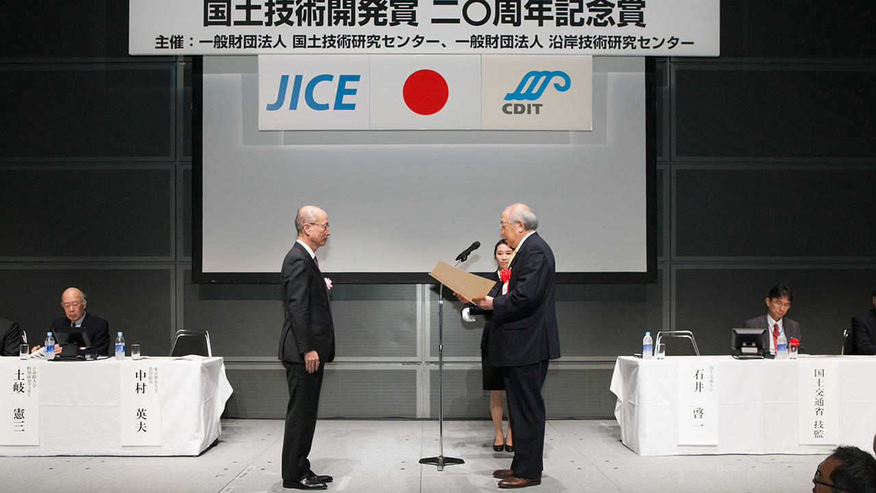 国土技術開発賞選考委員会中村英夫委員長(右)から表彰状を授与される大林組専務執行役員佐藤健人(左)