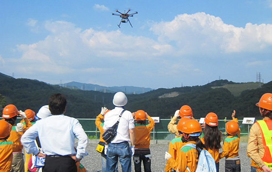 土量の計測に使用するドローン(小型無人機)の実演を興味深く見つめる子どもたち